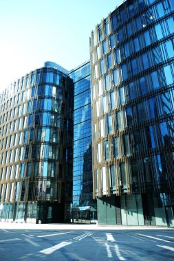 Yazın güneşli bir günde dış cephe inşa eden ofisler. Mavi gökyüzü pencerelerin camına yansımıştı. Gelecekçi iş konsepti.