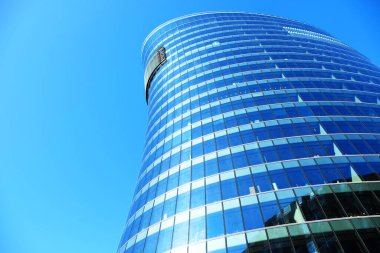 Yazın güneşli bir günde dış cephe inşa eden ofisler. Mavi gökyüzü pencerelerin camına yansımıştı. Gelecekçi iş konsepti.