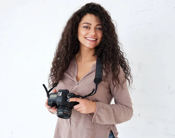 Retrato de mulher fican segurando fotocâmera digital e rindo sobre fundo branco em estúdio. — Fotografia de Stock