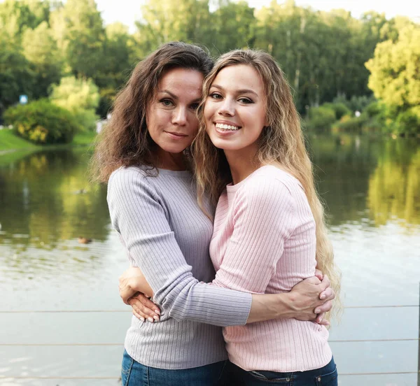 엄마와 딸은 호수 근처 공원에서 행복 한 가족들 과아름다운 여인들 과 포옹하고 있습니다 — 스톡 사진