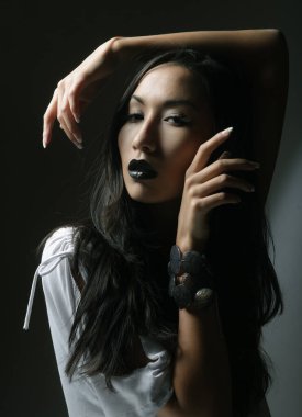 Siyah dudaklı, uzun saçlı, beyaz bluzlu güzel Asyalı kadın model.