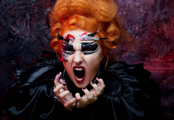 The witch screams furiously. Halloween picture. Red-haired woman with bright make up. — Stock Photo, Image