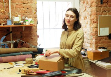 Esmer kadın dikiş atölyesinde paket kutusu katlıyor.