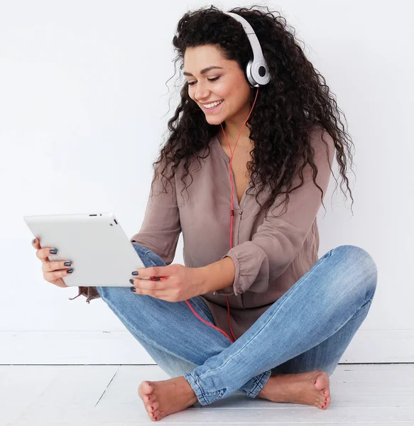 Αφροαμερικανή νεαρή γυναίκα κάθεται στο πάτωμα με tablet υπολογιστή και ακουστικά ακούγοντας μουσική στο σπίτι — Φωτογραφία Αρχείου