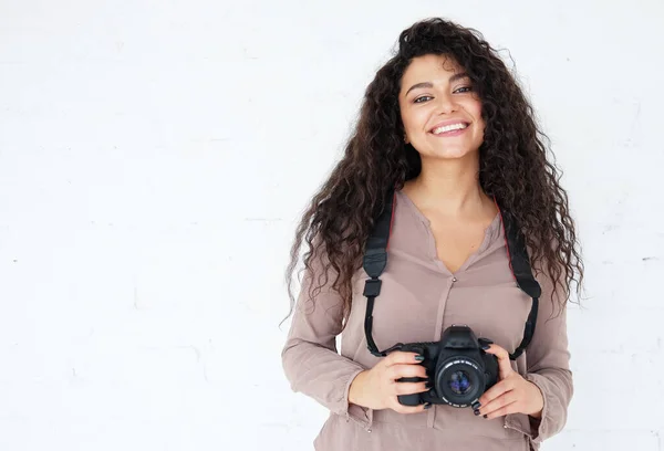 Portret kobiety z Afican trzymającej cyfrową fotokamerę i śmiejącej się z białego tła w studio. — Zdjęcie stockowe