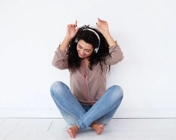 Χαρούμενη στιγμή. Αφρικανική γυναίκα ακούει τη μουσική της από το τηλέφωνό της με τα ακουστικά της, κάθεται στο πάτωμα στο σπίτι. — Φωτογραφία Αρχείου