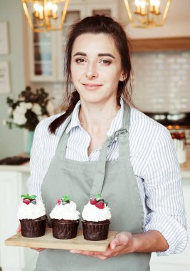 Elinde kek tutan genç fırıncı kadın. Mutlu, gülümseyen ve neşeli.