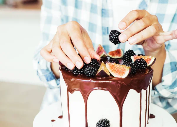 Кондитер украшает торт свежими ягодами и инжиром. — стоковое фото