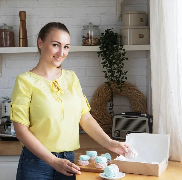 Kitchen, hobbies, people and cooking concept.Young woman pastry chef puts marshmallows in a box. Small home business. — Stock Photo, Image