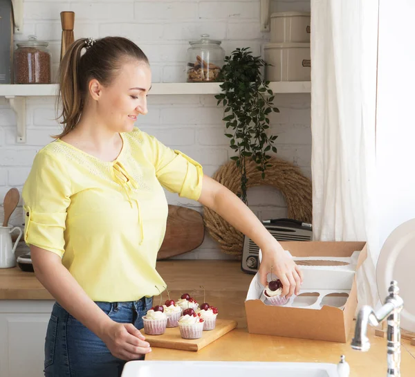 Young cook woman packs cupcakes in a box. Small home business. — Stock Photo, Image