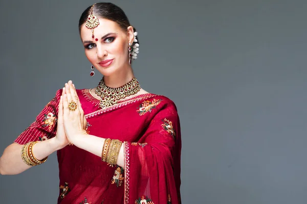 Portret pięknej indyjskiej dziewczyny w pozerce powitalnej dla Namaste hands .India kobieta w tradycyjnej sukience sari i biżuterii. — Zdjęcie stockowe