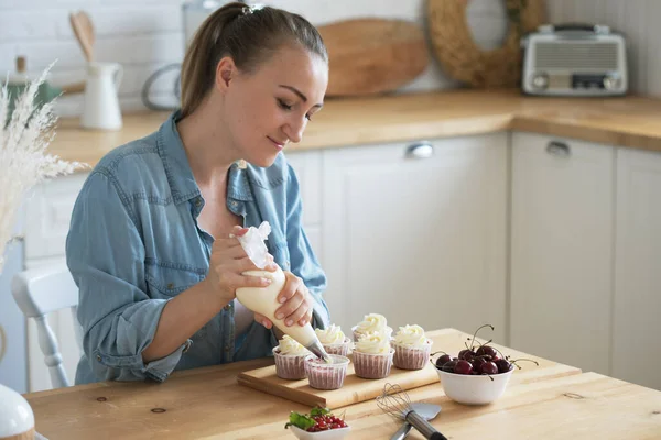 Young Woman making creamy top of cupcakes closeup. — Stock Photo, Image