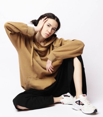 Güzel bir kadın, günlük kıyafetler giyiyor, beyaz bir sırt üzerinde poz veriyor.