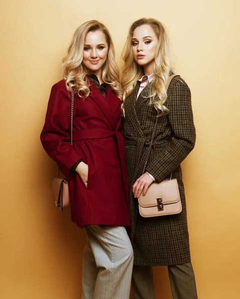 Divat portré két lány, legjobb barátok pózol beltéri bézs háttér visel téli stílusos kabát. — Stock Fotó