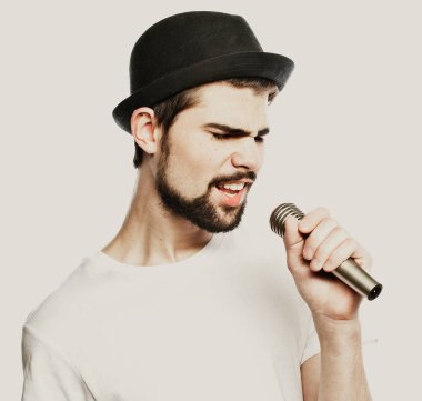 Genç adam mikrofonla şarkı söylüyor.
