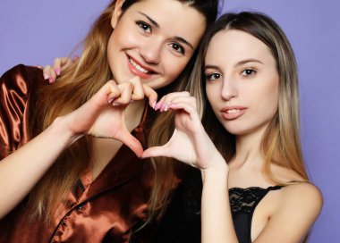 Yaşam tarzı ve insan konsepti: pijama giymiş iki güzel kız kucaklaşıp selfie çekiyor.