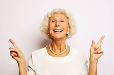 Fikir, ilgi ve insan konsepti - gülümseyen son sınıf kadınının portresi beyaz arka plan üzerinde işaret ediyor