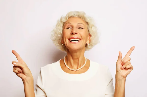 Idea, attention and people concept - portrait of smiling senior woman pointing finger up over white background — Stock Photo, Image