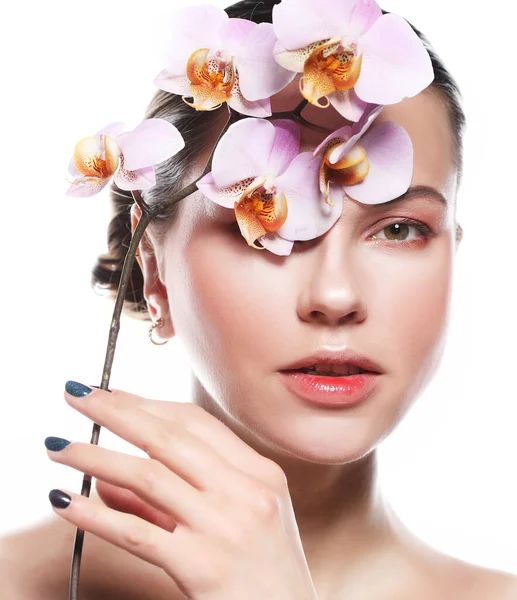 Krásná mladá žena s jasným make-up v růžových tónech drží orchidej, natáčení na bílém pozadí — Stock fotografie