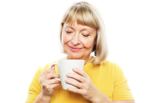 Mulher idosa alegre usar casual com sorriso bonito segurando uma xícara de café sobre fundo branco. — Fotografia de Stock