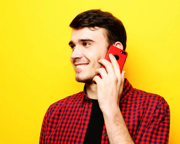 Glücklicher junger Mann telefoniert auf gelbem Hintergrund — Stockfoto
