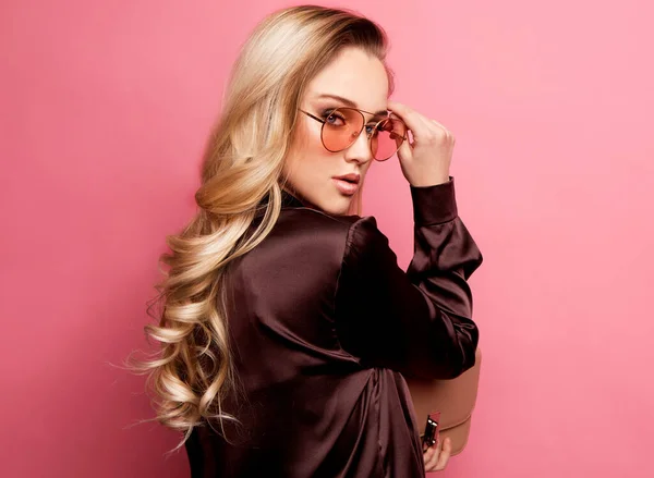 Beautiful blond woman in a blouse and pants wearing glasses, holding handbag — Stock Photo, Image