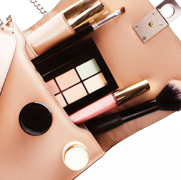 Vlakke lay van roze lederen vrouw tas open met cosmetica en accessoires, witte achtergrond. — Stockfoto