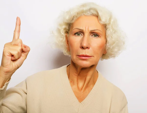 Idea, attention and people concept - portrait of smiling senior woman pointing finger up over white background — Stock Photo, Image