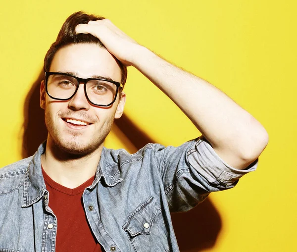 Portrait of young smiling man standing against yellow background — Stock Photo, Image