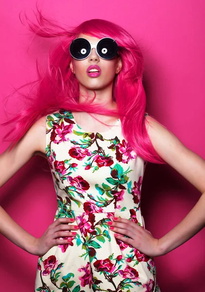 Young fashion female model with pink hair and big sunglasses over pink background — Stock Photo, Image