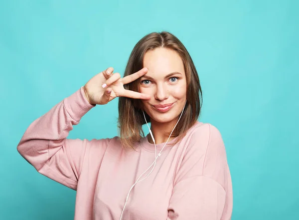 Retrato de una joven rubia feliz mostrando el gesto de victoria y guiño, sesión de estudio. — Foto de Stock