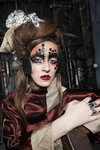 Mujer joven antes de una fiesta o carnaval. Maquillaje creativo brillante y peinado. Interior Steampunk. — Foto de Stock