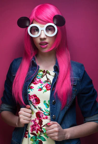 Young fashion female model with pink hair and big sunglasses over pink background — Stock Photo, Image