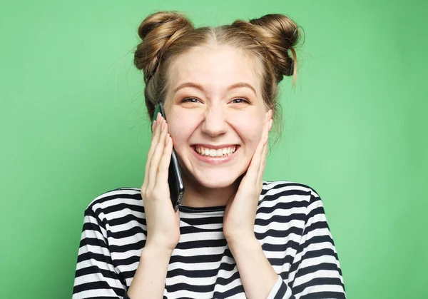 Joven mujer feliz vistiendo camisa a rayas hablando por teléfono mirando a la cámara, sobre fondo verde — Foto de Stock