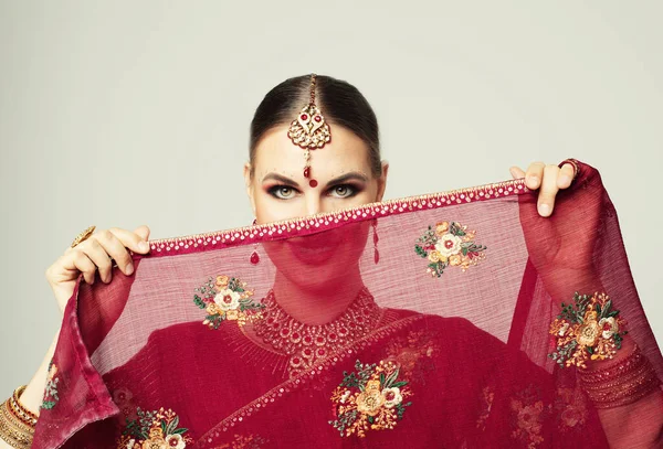 Young woman in Indian red sari with traditional jewelry.