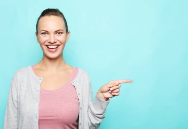 Yaşam tarzı, duygu ve gençlik kavramı: Mutlu gülümseyen güzel genç kadın mavi arka planda başparmak hareketi yapıyor