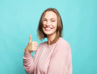 Yaşam tarzı, duygu ve genç insan konsepti: Mavi arka plan üzerinde parmaklarını gösteren neşeli mutlu bir kadının portresi