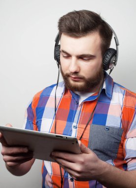 Açık gri arka planda kulaklık takan yakışıklı sakallı bir adamın stüdyo portresi..