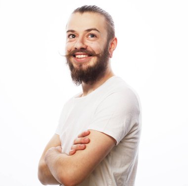 Beyaz tişörtlü yakışıklı genç adam kameraya bakıyor ve gülümsüyor.