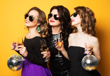 Üç neşeli genç bayan arkadaş disko topları ile şampanya içip eğleniyorlar.