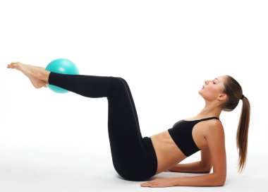Genç, zinde bir kadın jimnastik topuyla yoga egzersizi yapıyor. Spor ve yoga konsepti.