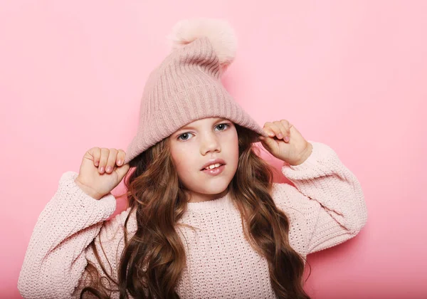 Άνθρωποι, την παιδική ηλικία και την έννοια της μόδας: κοριτσάκι φορώντας ροζ καπέλο χειμώνα και πουλόβερ σε ροζ φόντο — Φωτογραφία Αρχείου