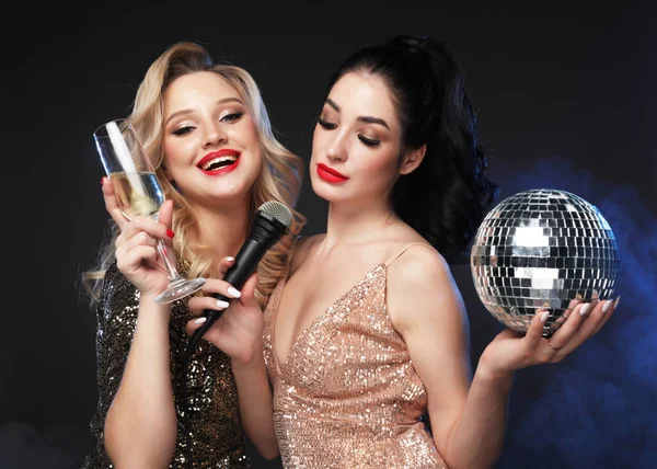 Portrait of elegant young women with a champagne glasses and microphone at celebration New Year. — Stock Photo, Image