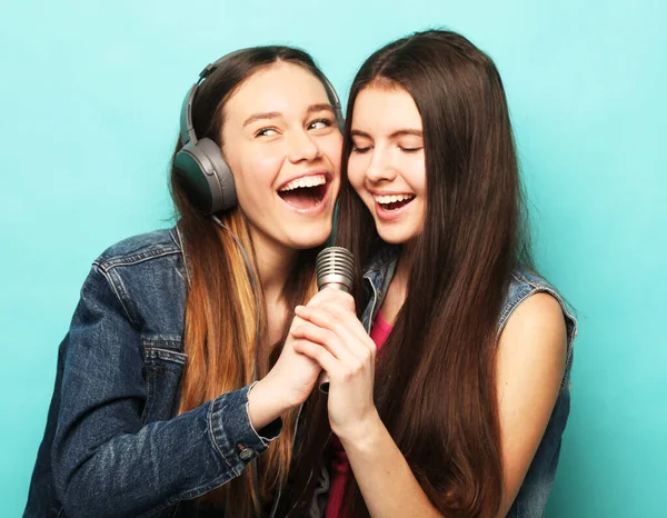 Style de vie, émotion et concept de personnes : Deux jeunes amies debout ensemble et écoutant de la musique et chantant — Photo