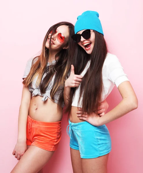 Счастливые улыбающиеся симпатичные подружки-подростки обнимающиеся на розовом фоне — стоковое фото