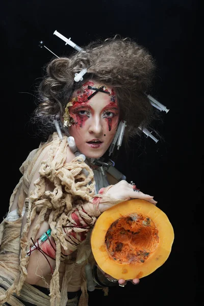 Mujer con maquillaje creativo y estilo de pelo loco con calabaza sobre fondo oscuro. Tema Halloween. — Foto de Stock