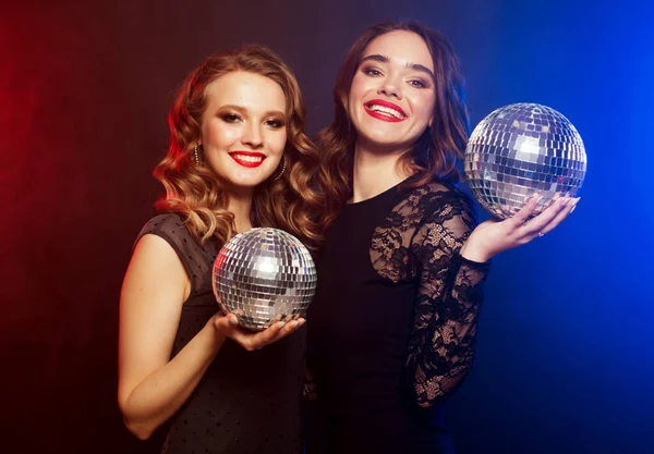 Festa, emoção e conceito de pessoas: Duas mulheres com bolas de discoteca sobre fundo azul — Fotografia de Stock