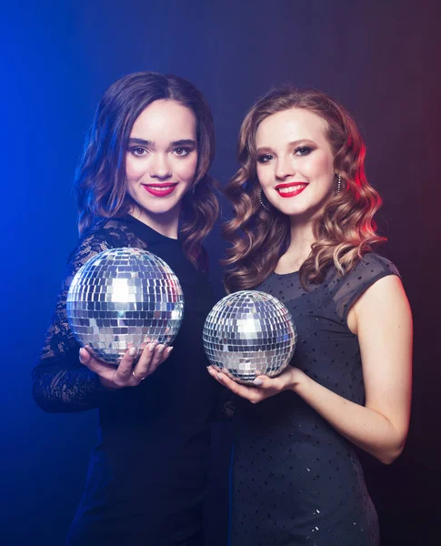 Párty, emoce a lidé koncept: dvě ženy s disco koule přes modré pozadí — Stock fotografie