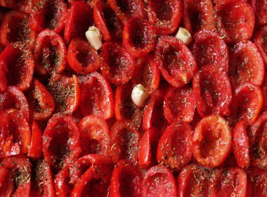 Domatesler fırın tepsisine konmuş, pişirmeye hazır. Güneşte kurutulmuş domates. Kapat..