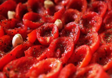 Domatesler fırın tepsisine konmuş, pişirmeye hazır. Sarımsaklı güneşte kurutulmuş domates. Gıda arkaplanı.